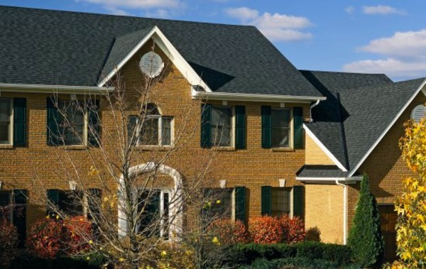 Large brick front house with dark gray shingled roof.